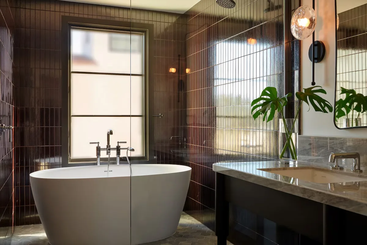 Guest bathroom with dark glazed Japanese tile, freestanding tub and marble vanity